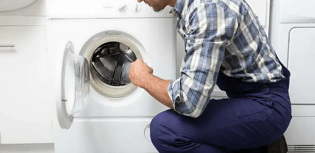 Handyman inspecting a dryer drum and internal parts for repair in Grand Rapids, MI