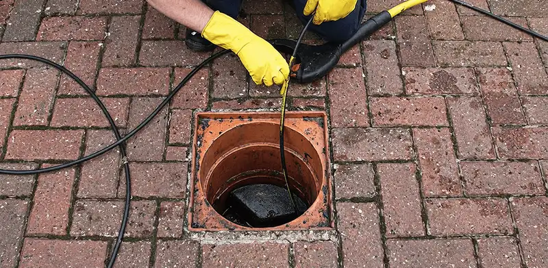 Drain cleaning technician using a drain snake to clear a clogged drain in Grand Rapids, MI
