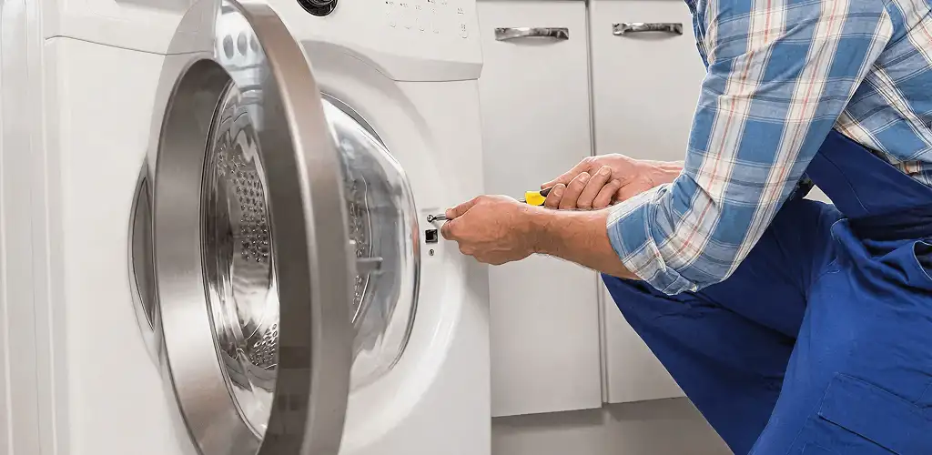 Handyman repairing a clothes dryer and checking electrical connections in Grand Rapids, MI