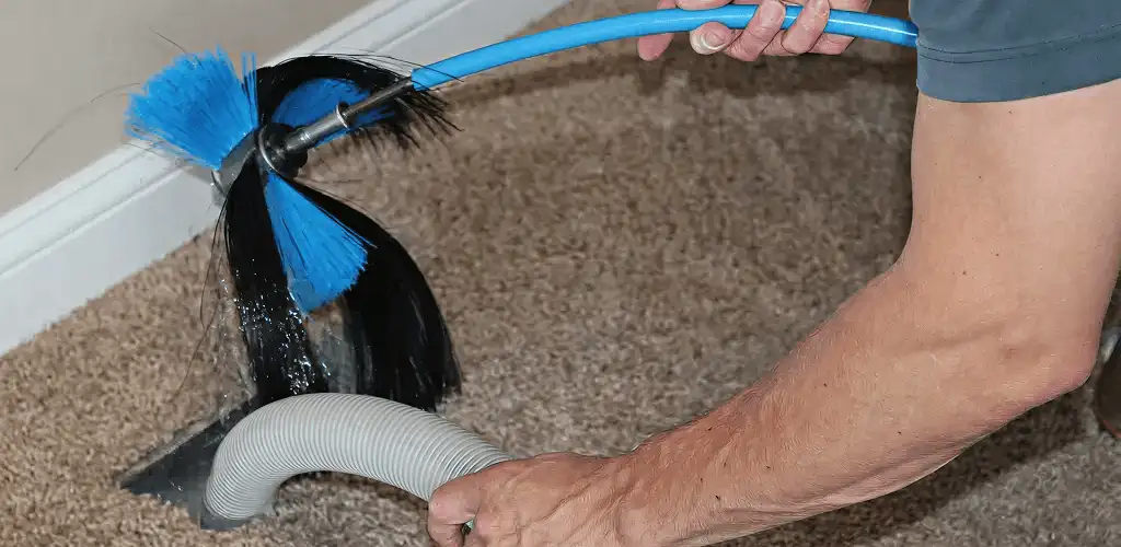 Dryer vent cleaning technician brushing lint from a vent line in Grand Rapids, MI