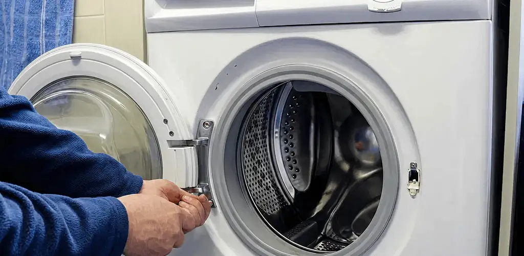 Washing machine repair handyman checking a front-load washer door and latch in Grand Rapids, MI