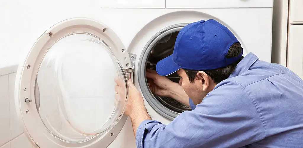 Washing machine repair handyman inspecting a front-load washer drum in Grand Rapids, MI