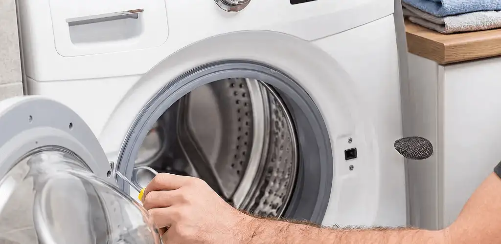 Handyman repairing a front-load washing machine and inspecting the drum in Grand Rapids, MI