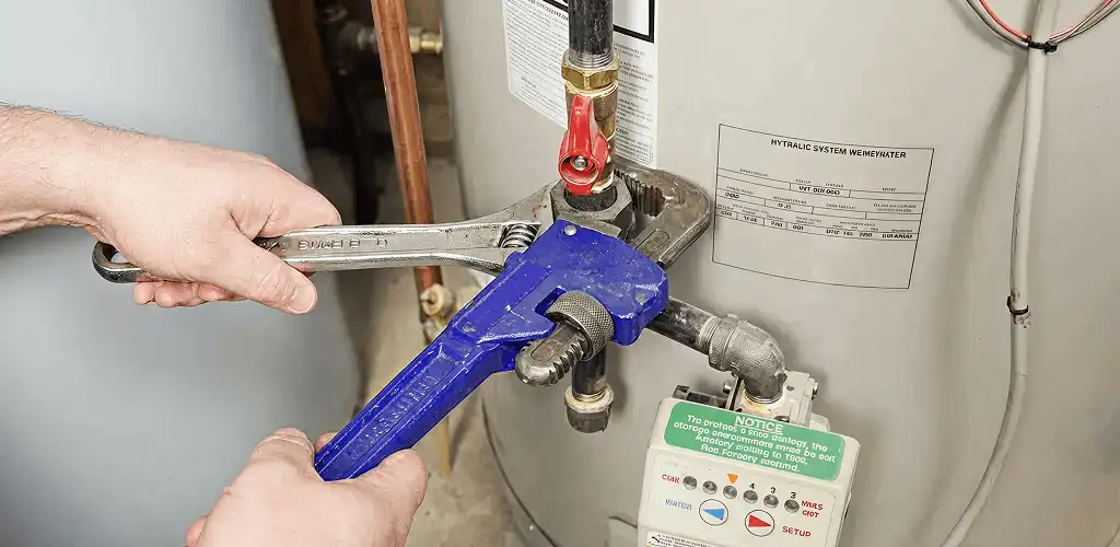 Water heater repair technician tightening the shutoff valve and supply line in Grand Rapids, MI